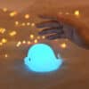 Cute, squishy white silicone dolphin night light emitting a soft, warm glow for a nursery or bedroom.