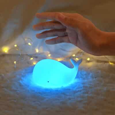 Adorable mini whale night light made of soft white silicone, glowing with a soft and comforting light.