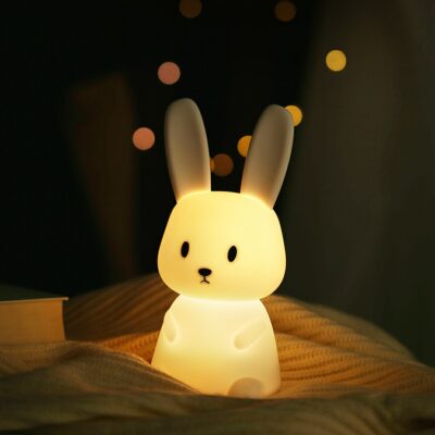 Night Light Soft, squishy silicone bunny lamp with long ears, emitting a warm and gentle glow on a bedside table.