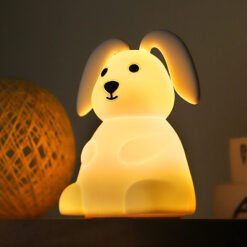 Soft silicone bunny night light lamp in a sitting pose, emitting a warm, soothing glow on a dark surface.